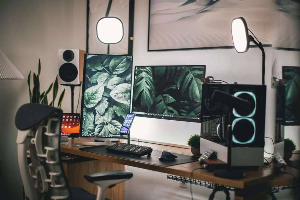 A PC set up for streaming with two monitors, two lights and other streaming hardware on a desk with large speakers, this setup would be good to find out how to stream a vtuber.