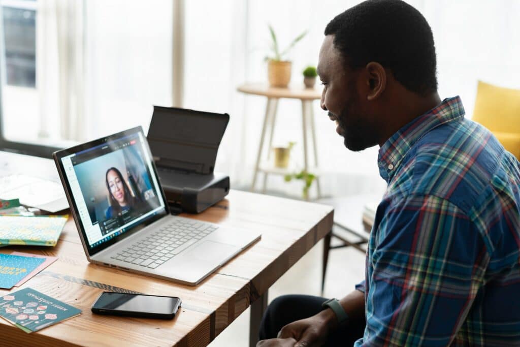 Synchronous Vs Asynchronous Communication on display here as a person talks to someone on a zoom call which could also be recorded.