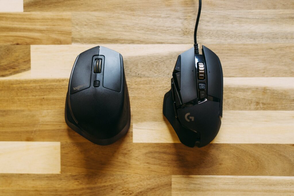 Two affordable gaming mice sat next to eachother on a desk, one wired and one wireless.