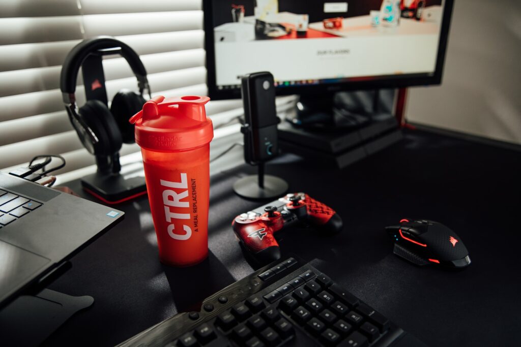 A desk with a streaming setup on it, keyboard, mouse, PS4 control pad, laptop, monitor, a microphone and a heaset, checking all your gear is important before you stream.