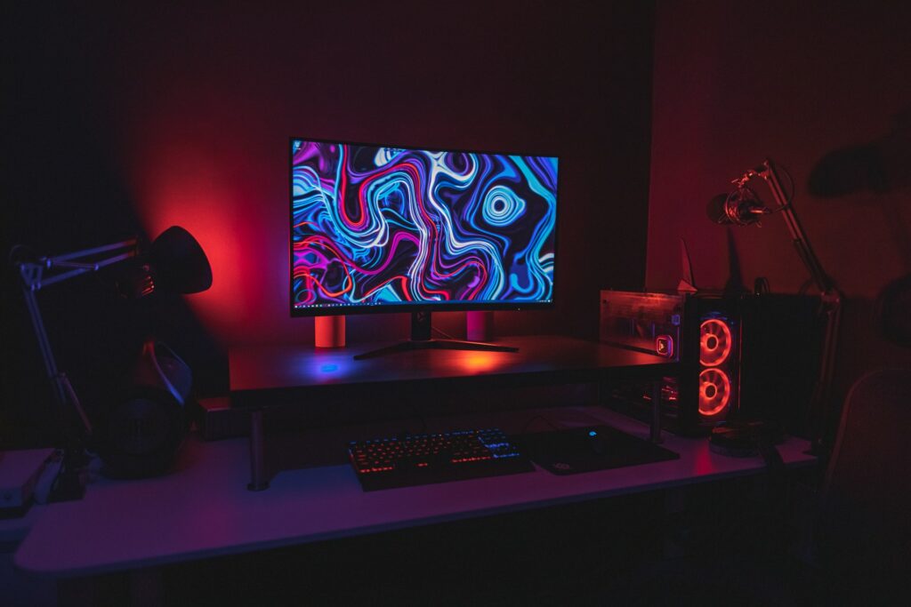 A streaming PC setup on a desk with a mic, monitor, keyboard, mouse and mood lighting for a part-time streamer.