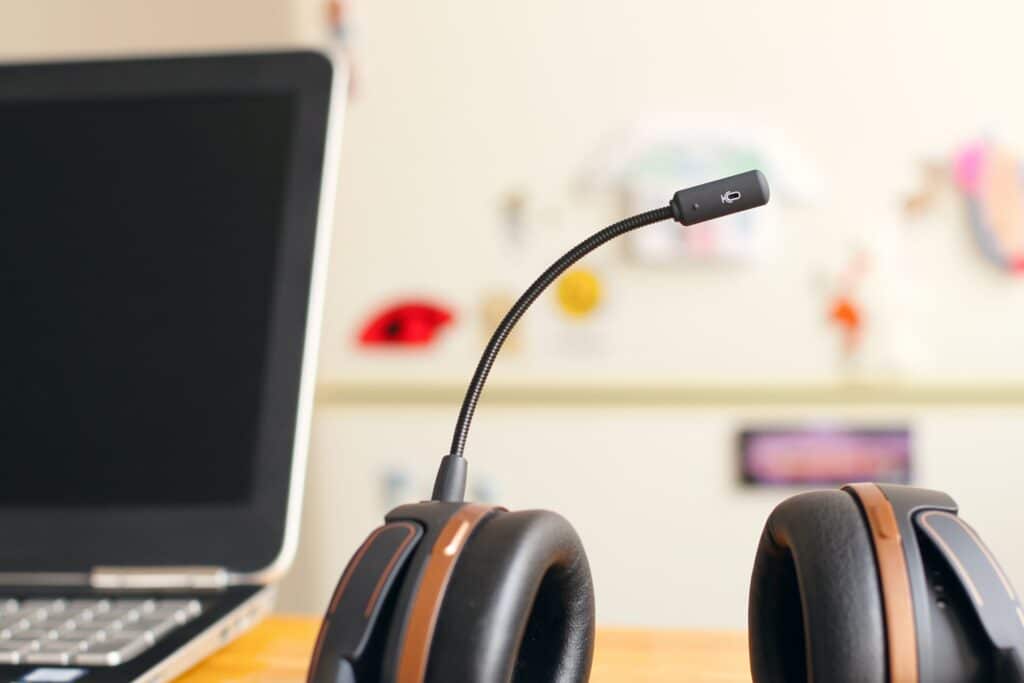 A headset microphone sat on a desk next to a laptop is one of the best budget mics.
