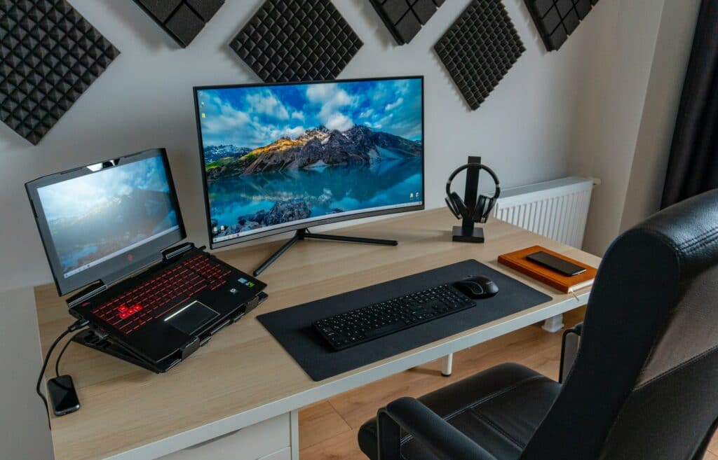 A minimal streaming setup using a gaming laptop on a desk connected to a monitor looking for the best YouTube live features.