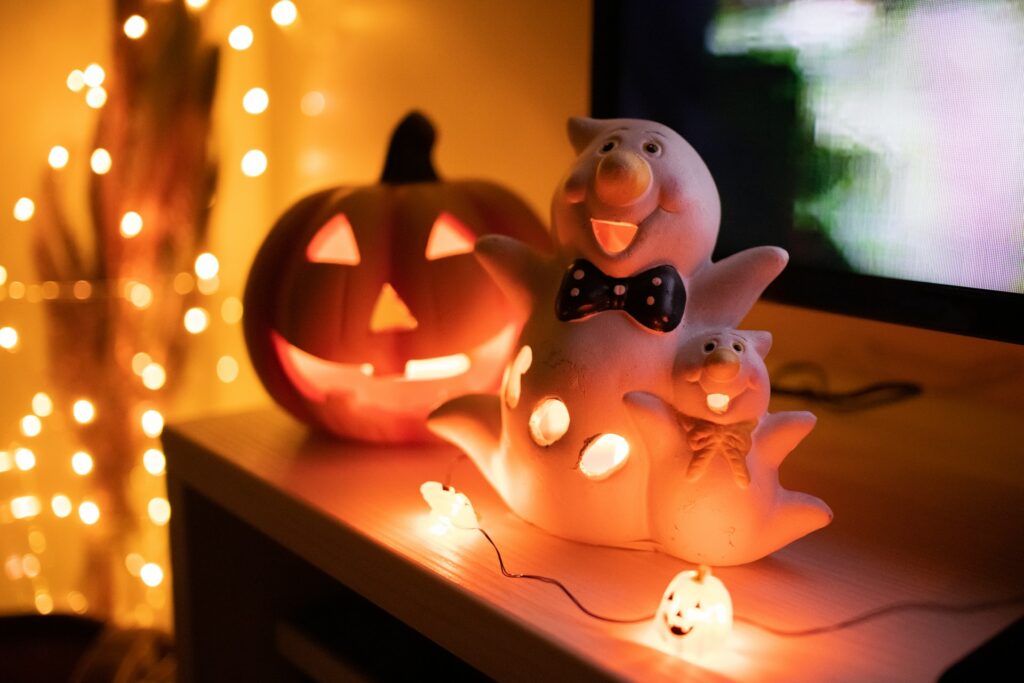 Pumpkin lights, ghost candle holders and a jack'o'lantern on a desk.