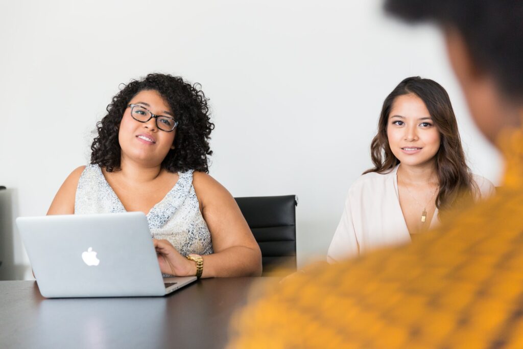 Two people looking at someone else with a laptop on the table as they take part in a virtual job interview.