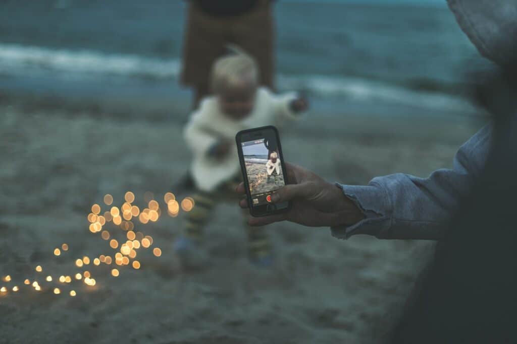 Someone taking a picture of their child at the beach using a smartphone as a webcam