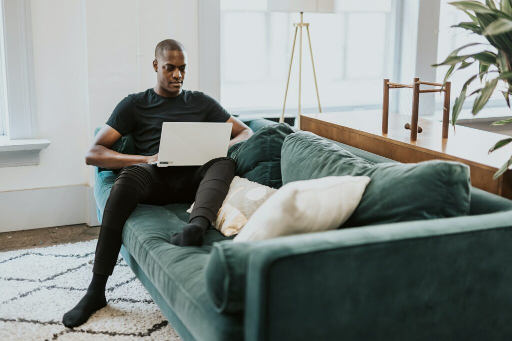 A man sat comfortably on his sofa is making a better online presentation with XSplit Presenter on their laptop.