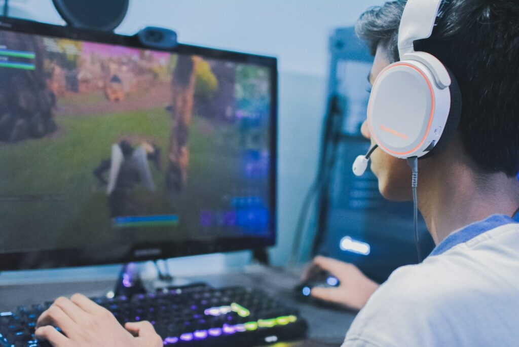 A person viewed from behind with a gaming headset on playing Fornite they're probably looking for a way to improve live stream quality as well.