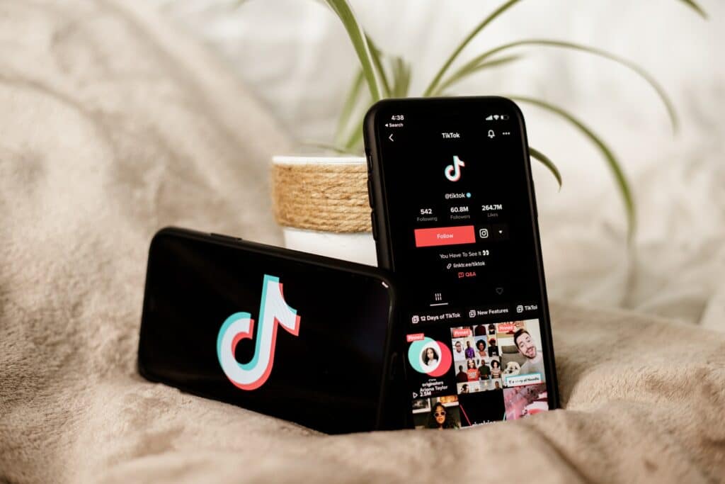 Two phones sit next to a potted plant, both showing TikTok, you can stream to TikTok from your desktop PC with XSplit Broadcaster.