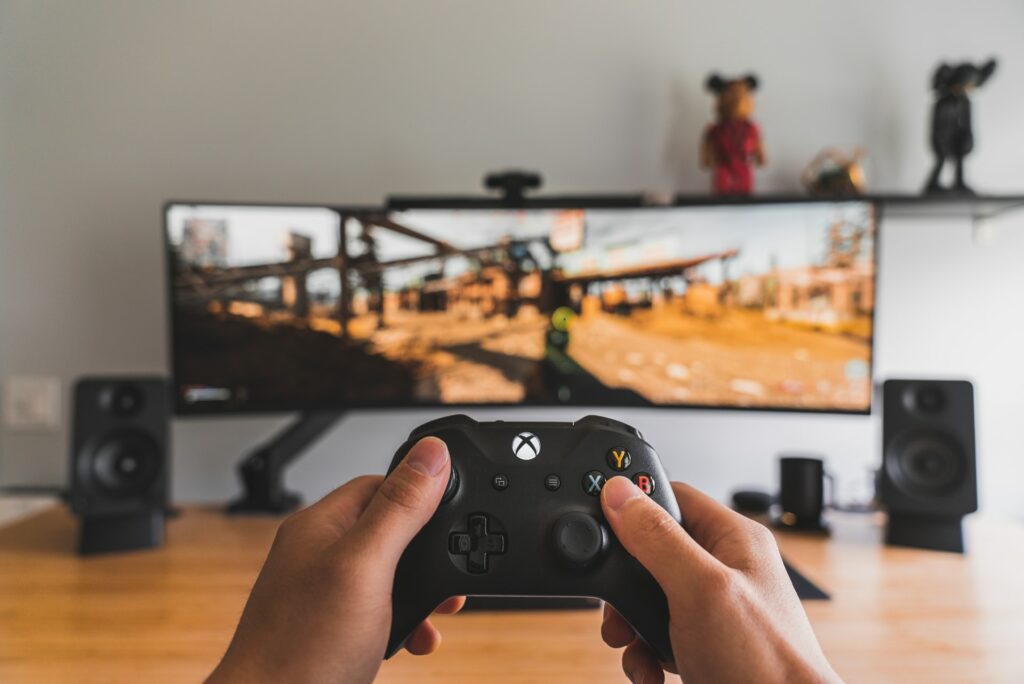 An Xbox One controller is being held in front of a wide monitor, gameplay could be one way to improve your viewership.