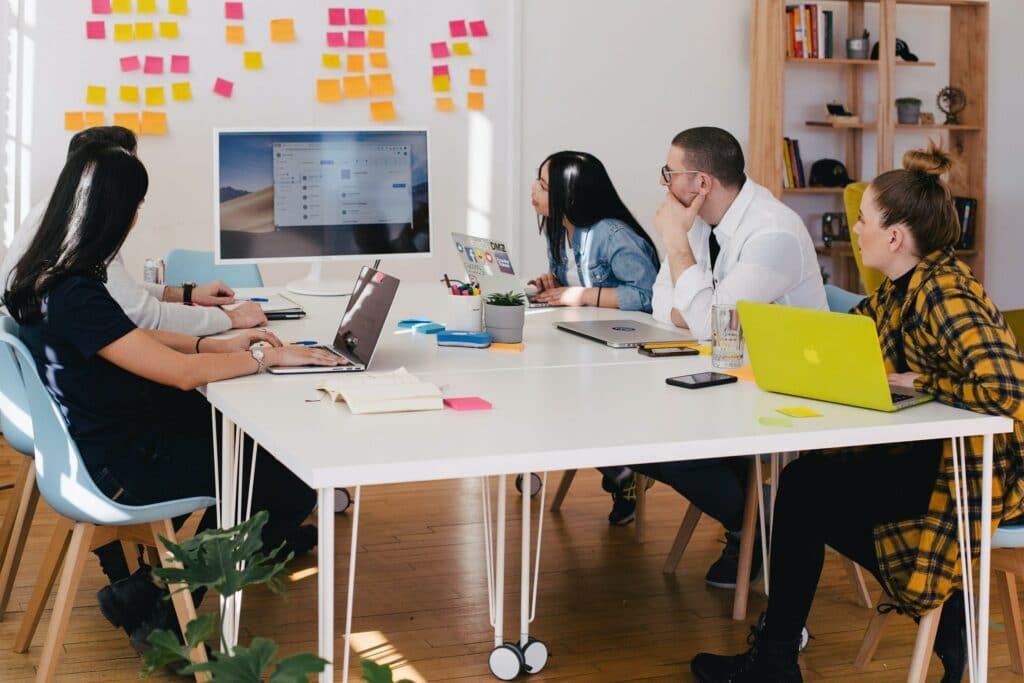 People sat around a desk looking at a presentation being given on a screen which can be key to improve workplace communications