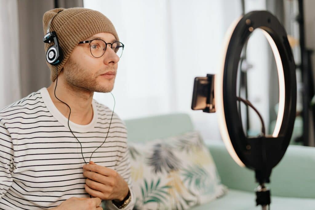 A person sat in front of a ring light with headphones on is one of the best lighting for a webcam.