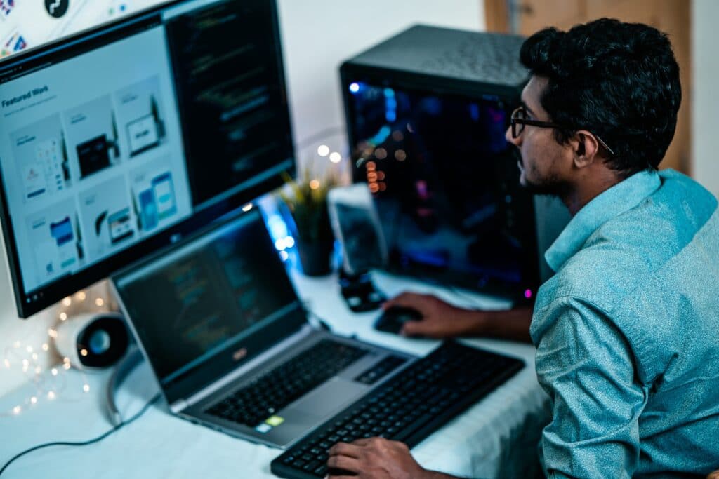 A person working at their desktop work place running multiple remote team management software.