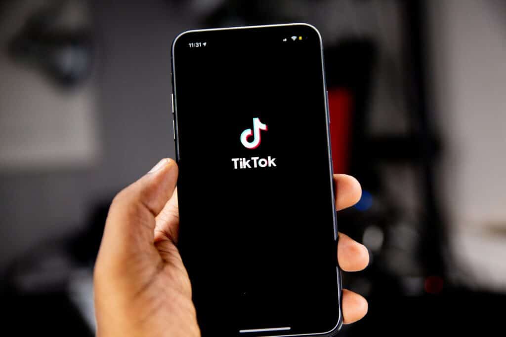 A person holding a phone which is displaying the TikTok logo which could be a part of the future of live streaming.
